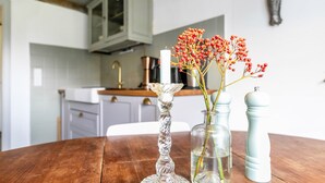 A wooden table with a candle, a vase with red berries, and a salt shaker.