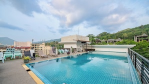 Una piscina sul tetto con vista sugli edifici e le colline circostanti.
