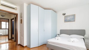 A bedroom with a bed, a wardrobe, a mirror, and a painting on the wall. - GuestHost - Milano Chiesa Rossa Comfy Apartment (Milan)