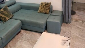 Una sala de estar con un sofá modular, una mesa de centro y un cuadro en la pared.