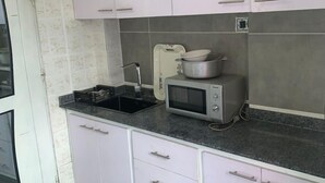 Una cocina con armarios blancos, un microondas y un lavamanos.