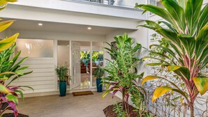 A modern house with a glass door entrance, surrounded by various potted plants.