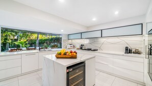 A modern kitchen with white cabinetry, a marble backsplash, and a built-in dishwasher.