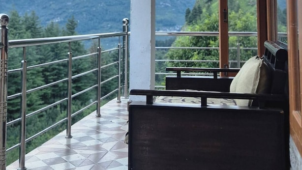 Un balcón con piso a cuadros, un banco de madera y vista a las montañas.