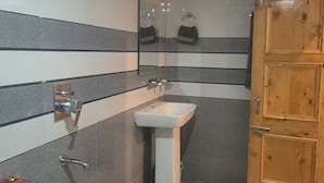 Un baño con lavamanos, espejo y puerta de madera.