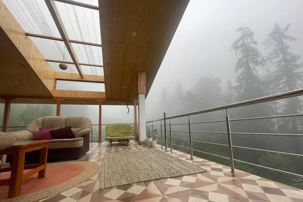A spacious balcony with a checkered floor, a sofa, a small table, and a hanging plant.