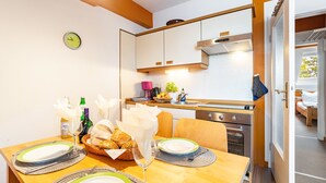 Uma cozinha compacta com área de jantar, um relógio e vista para a sala de estar.