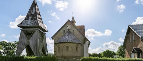 A church with a clock tower, a cobblestone pathway, and a bench.