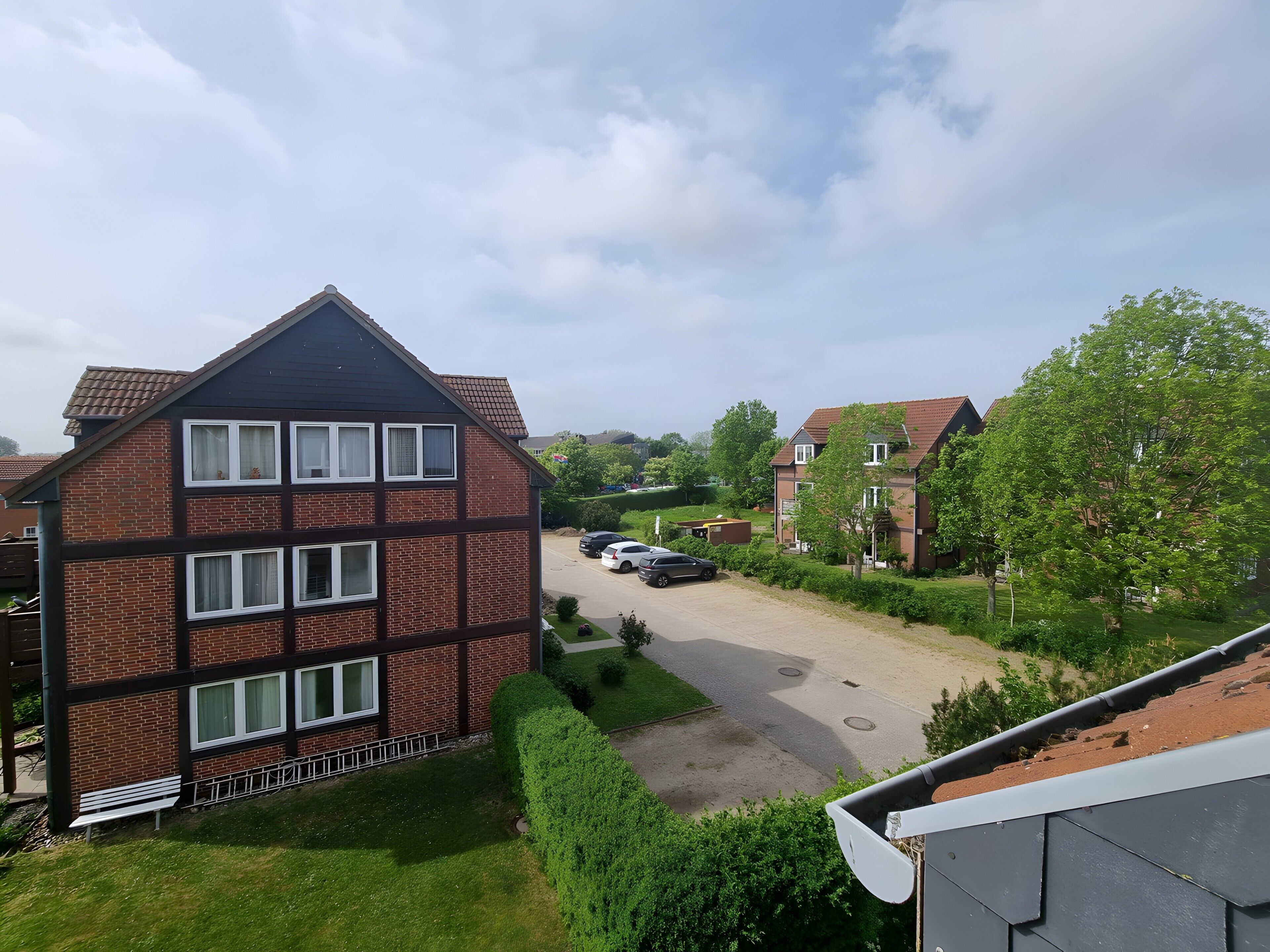 A residential building with a brick facade, multiple windows, and a sloped roof.
