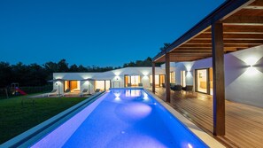 Une villa moderne dotée d’une piscine, d’un espace salon extérieur et d’un patio couvert.