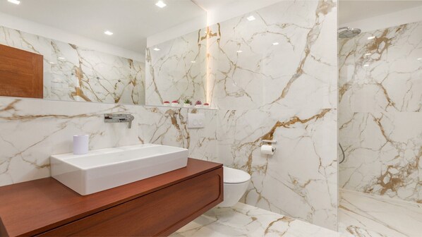 A modern bathroom with a marble vanity, a toilet, and a shower area.