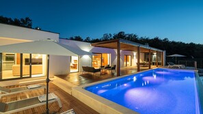 A modern house with a swimming pool, outdoor seating, and a covered patio area.