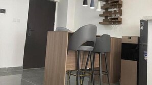 Moderni keittiö, jossa on puinen työtaso, kaksi baarituolia, riippuvalaisimet ja sisäänrakennettu viiniteline.