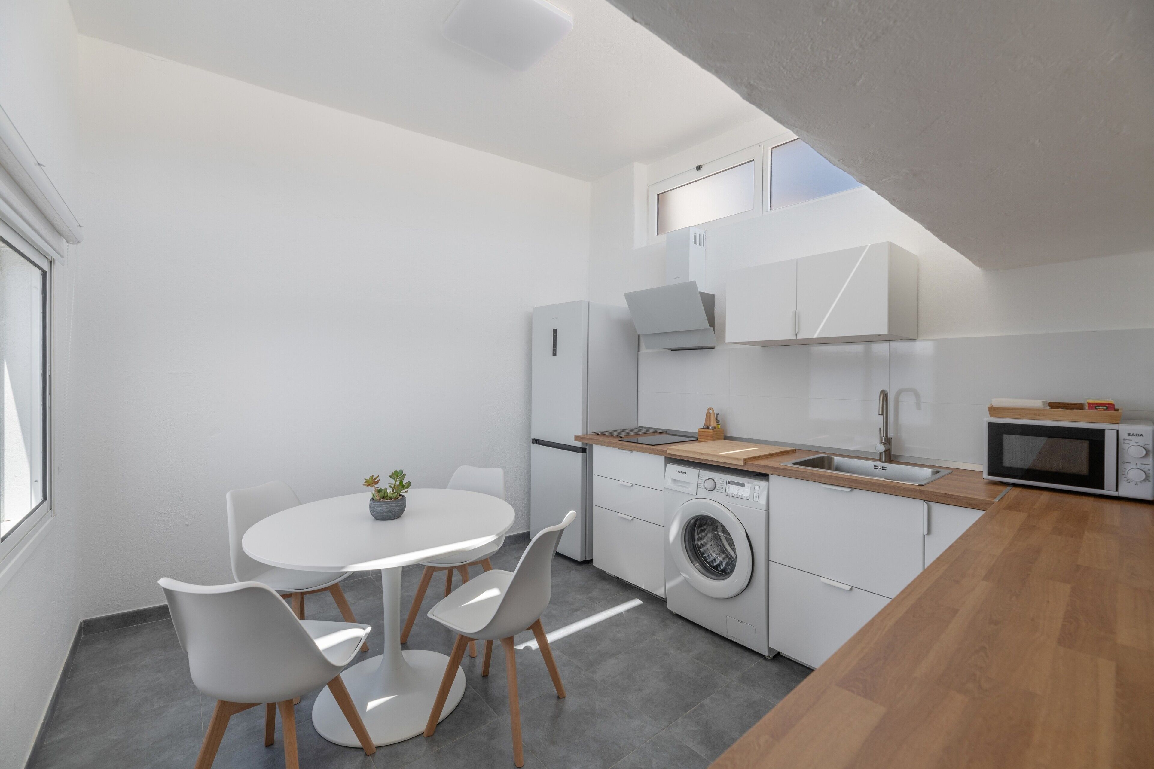 A modern kitchen with a dining area, built-in appliances, and a small window.