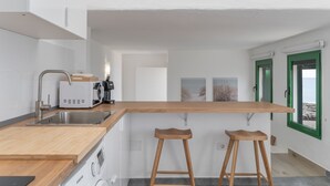 A modern kitchen with a wooden countertop, stainless steel sink, and two wooden stools. - Holiday Home 'Callao 1' with Sea View, Wi-Fi and Air Conditioning (Playa Quemada)