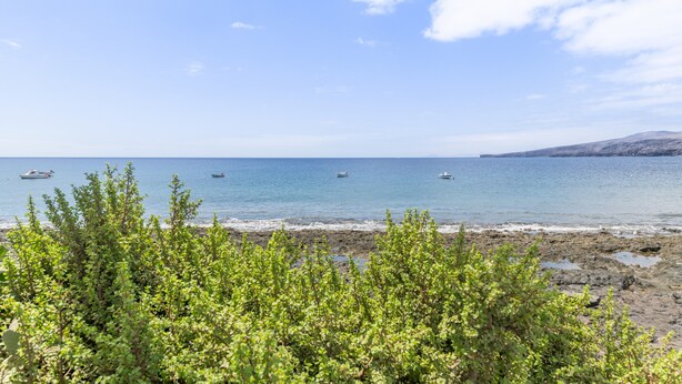 A beach with boats, rocky shore, and green vegetation. - Holiday Home 'Callao 1' with Sea View, Wi-Fi and Air Conditioning (Playa Quemada)