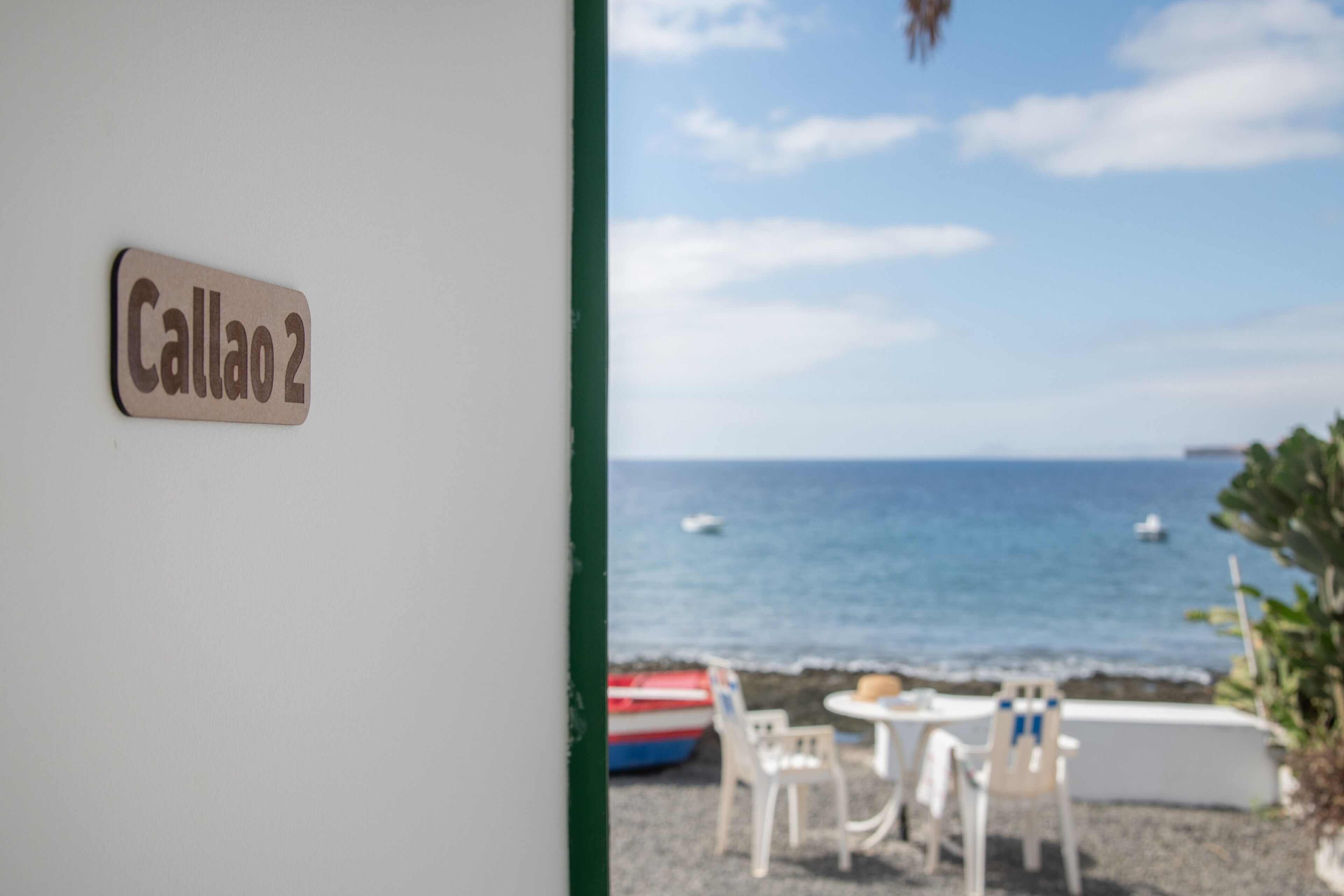 Blick auf einen Strand mit einem Schild, auf dem 'Callao 2' steht, und einem Tisch mit Stühlen.