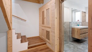 A wooden staircase leading to a bathroom with a wooden door, a mirror, and a sink. - Holiday Home 'Anton' with Mountain View, Private Terrace and Wi-Fi (Gerlosberg)