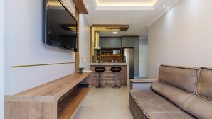 Un soggiorno moderno con una panca in legno, un divano e una TV a parete.