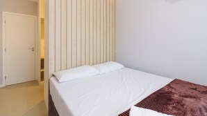 Una camera da letto con un letto, una testiera in legno, un condizionatore d'aria bianco e una coperta marrone.