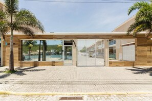 A modern building entrance with a glass door, a visible address number, and a staircase leading to an upper level. - Condominium on the Edge of the Cabo Frio Channel - CFR (Cabo Frio)