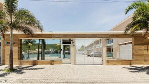 Ingresso moderno di un edificio con porta in vetro, numero civico ben visibile e una scalinata che conduce a un piano superiore.