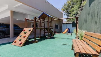 A playground with a climbing wall, swings, and a slide.