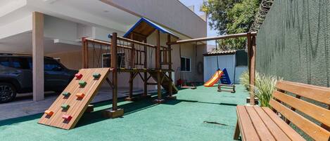 A playground with a climbing wall, swings, and a slide.