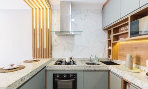 A modern kitchen with a gas stove, oven, and built-in dishwasher. - Condominium on the Edge of the Cabo Frio Channel - CFR (Cabo Frio)