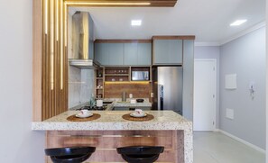 Uma cozinha moderna com bancadas de granito, armários de madeira e eletrodomésticos de aço inoxidável.