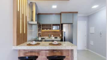 Een moderne keuken met granieten aanrechtbladen, houten keukenkastjes en roestvrijstalen apparatuur.