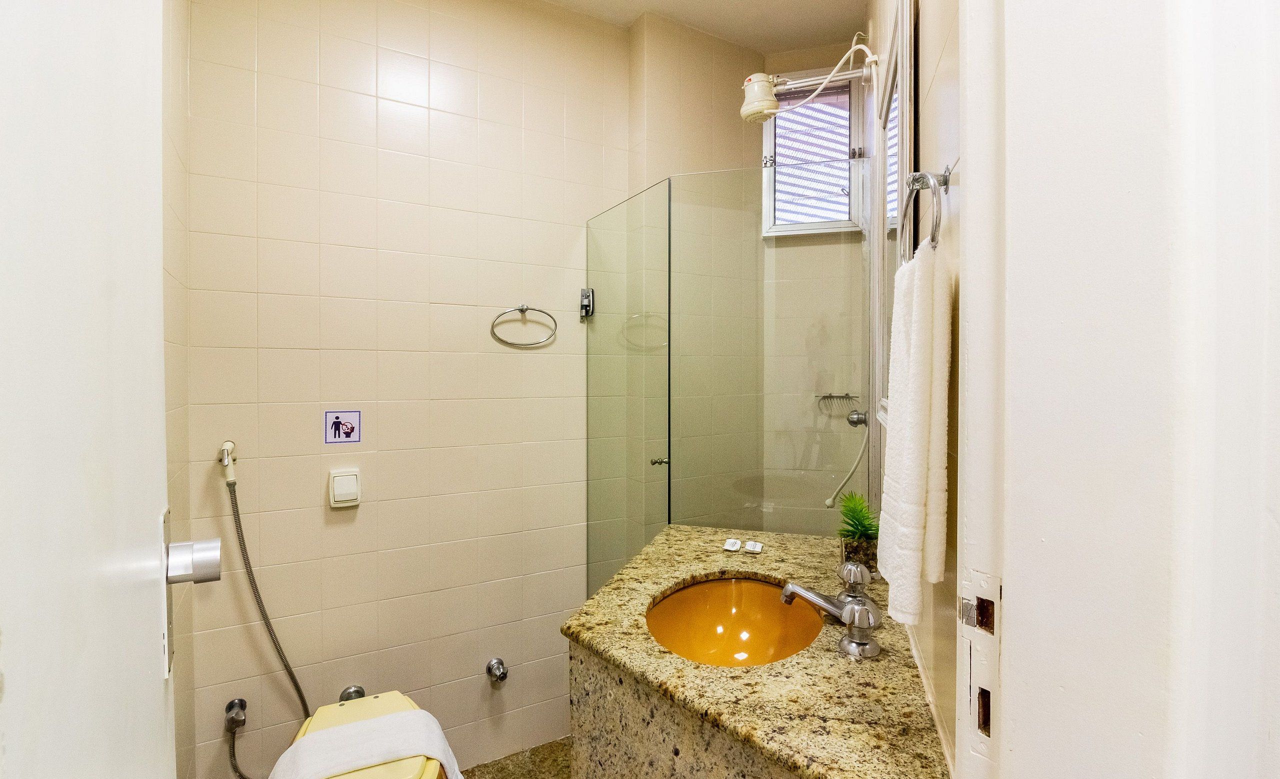 Un baño con lavamanos de granito, cabina de ducha con mampara de vidrio y un inodoro.