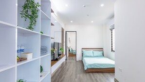 Un dormitorio moderno con una cama de madera, un armario blanco y un pequeño balcón con una planta.