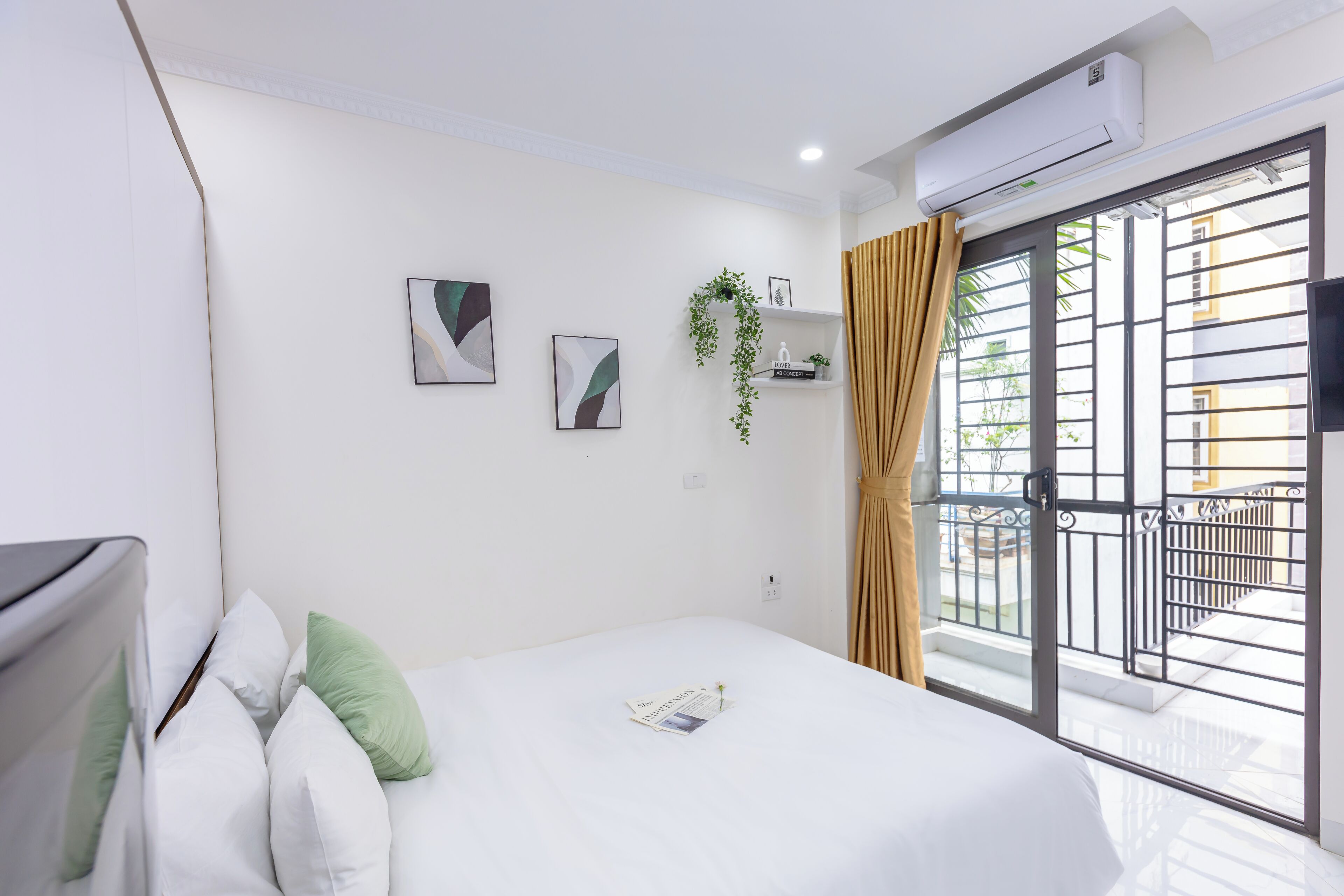 Habitación de hotel con cama, televisor de pantalla plana, ventana con cortinas y aire acondicionado.