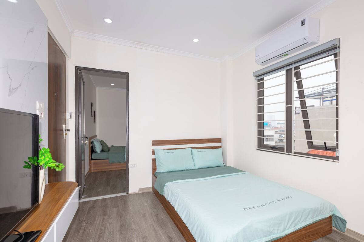 Een slaapkamer met een bed, een televisie, een plant en een airconditioner.