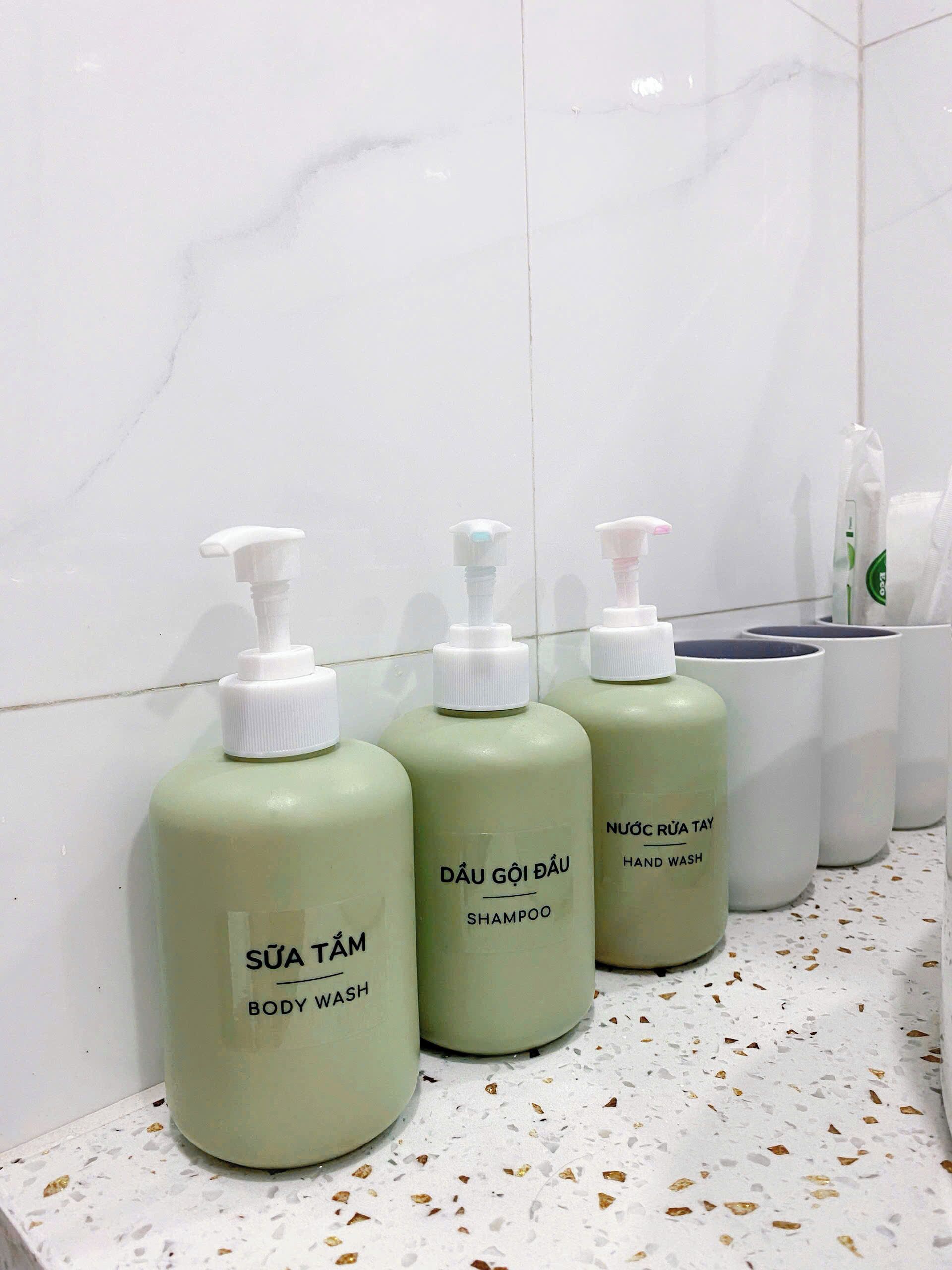 Tres botellas de jabón de baño y champú sobre una encimera blanca.