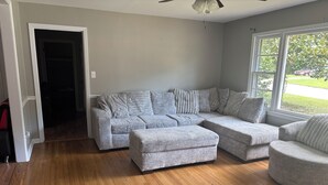 Ein Wohnzimmer mit Ecksofa, Hocker und rundem Sessel.