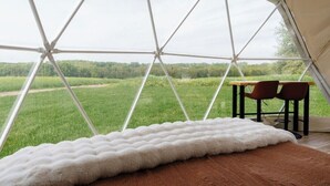 A tent with a view of a green field, a white furry rug, and two chairs. - The Sunset Dome- a private escape, with breathtaking sunsets, rooted in nature. (Guelph/Eramosa)
