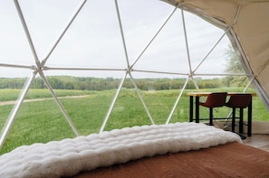 A tent with a view of a green field, a white furry rug, and two chairs. - The Sunset Dome- a private escape, with breathtaking sunsets, rooted in nature. (Guelph/Eramosa)