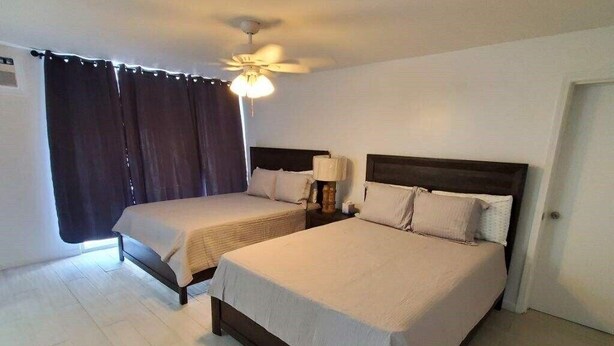 Une chambre d’hôtel avec deux lits, un ventilateur de plafond et une fenêtre avec des rideaux.