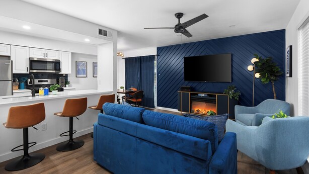 Un salon moderne avec un canapé bleu, un téléviseur à écran plat fixé sur un mur bleu et une cheminée.