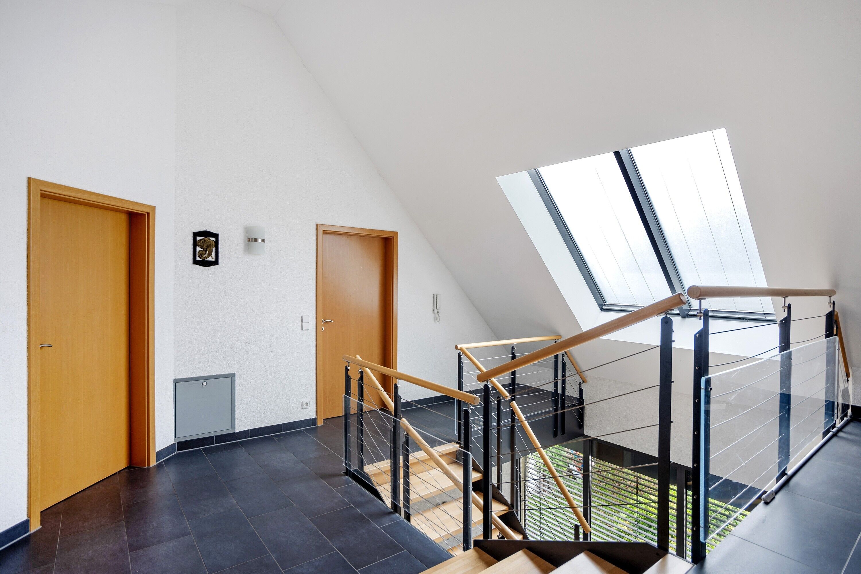 Ein modernes Interieur mit Holztür, einem kleinen gerahmten Bild und einem Oberlicht.