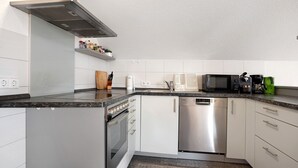 Une cuisine moderne dotée de meubles blancs, d’un lave-vaisselle en acier inoxydable, d’un four à micro-ondes et d’un four encastré.