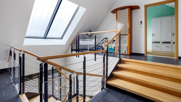Un intérieur moderne avec un escalier, une verrière et une vue sur une pièce dotée de meubles de rangement.