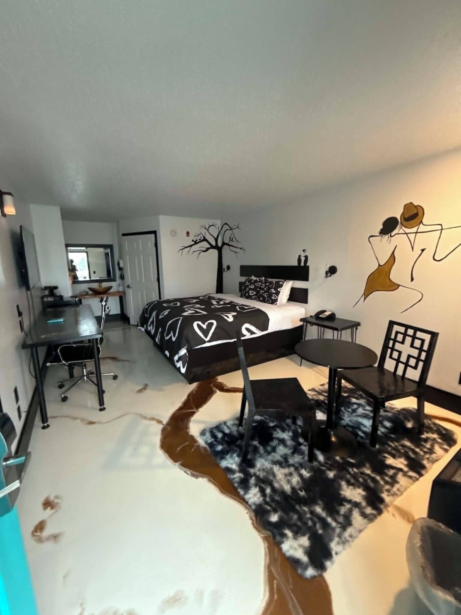 Un dormitorio con cama, escritorio, silla y un mural en la pared.