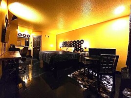 Una habitación con cama, escritorio, silla, tocadiscos en la pared y una puerta.