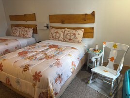 Una cama doble con ropa de cama floral, un cabecero de madera y una mesita de noche pequeña con una lámpara.