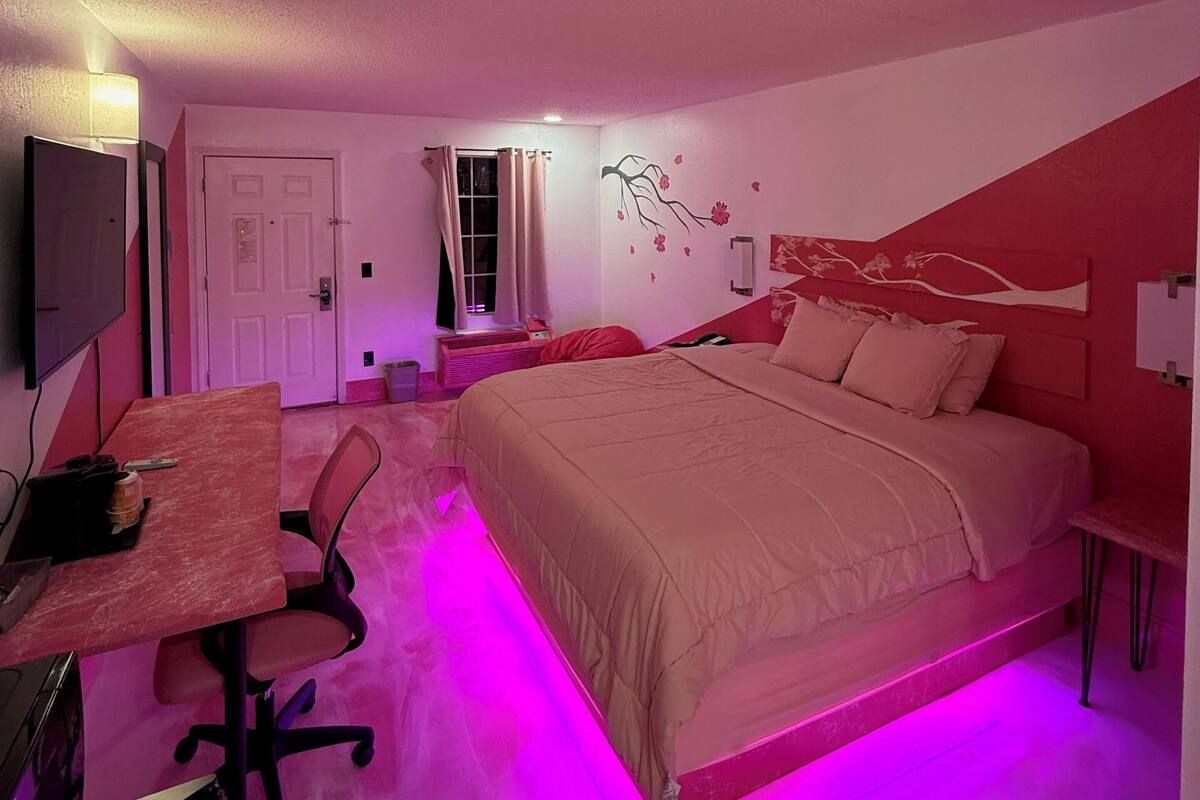 Un dormitorio con cama, escritorio, silla y ventana con cortinas.