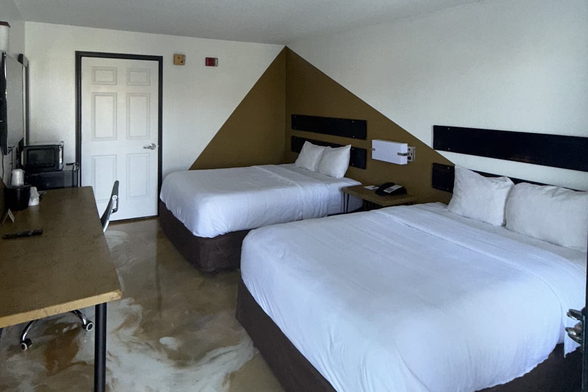 Una habitación de hotel con dos camas, un escritorio y una televisión.