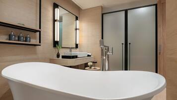 A modern bathroom with a freestanding bathtub, a vanity with a mirror, and a shower area.